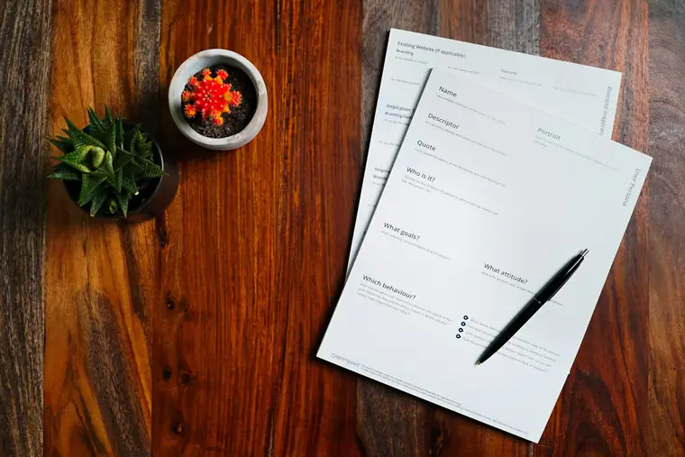A wooden table topped with papers and a pen